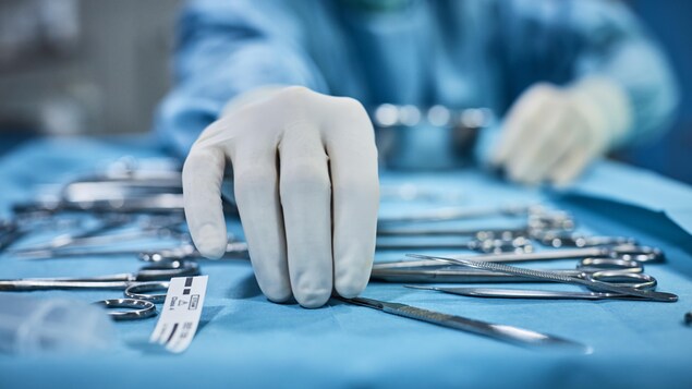 Le chirurgien ramasse un instrument chirurgical sur le plateau.