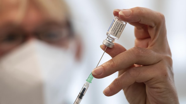Gros plan sur une personne qui remplit une seringue à partir d'une fiole du vaccin contre la COVID-19.