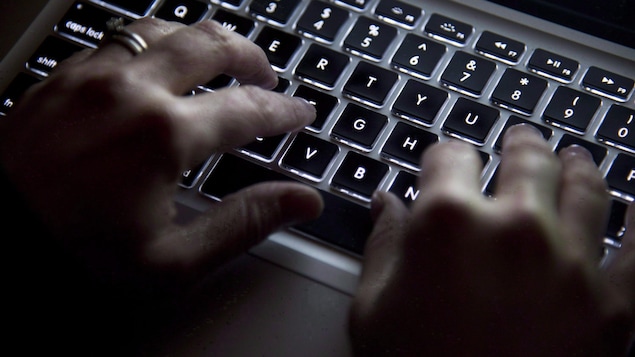 Des mains sur un clavier d'ordinateur.