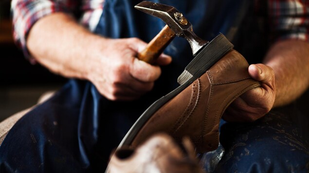Un cordonnier répare le talon d'un soulier.