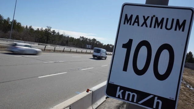 Un panneau de limitation de vitesse à 100 km/h à côté d'une autoroute