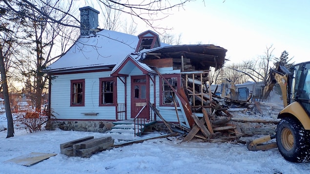 Une maison ancienne en train de se faire démolir par une pelle mécanique.