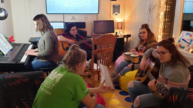 Des jeunes jouent de la musque dans un salon.
