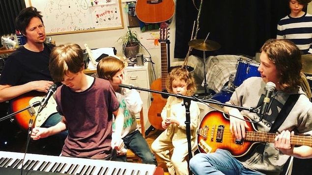 L'auteur-compositeur-interprète Manuel Gasse et ses enfants, dans leur studio maison, jouant chacun un instrument de musique.