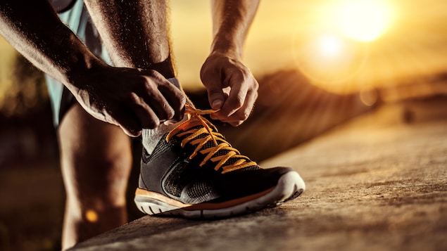 Un homme se prépare pour une course à pied en attachant les lacets de son soulier.