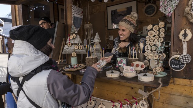 Marché de Noël de Baie Saint-Paul du 1 au 3 décembre 2017. Une artisane, dans sa maisonnette, discute de ses produits avec une cliente. Marché de Noël de Baie Saint-Paul du 1 au 3 décembre 2017. Une artisane, dans sa maisonnette, discute de ses produits avec une cliente.