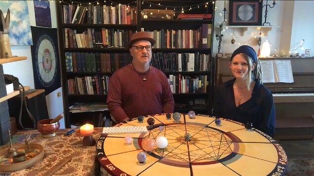 Martin Comtois et sa collègue devant une table ronde d'astrologie avec des planètes en pierre posées dessus.