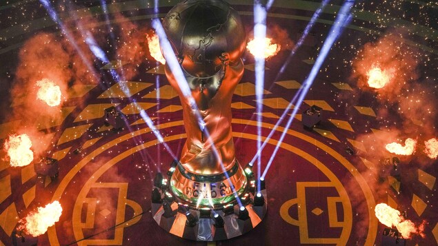 Des feux d'artifices autour d'une imitation géante du trophée de la Coupe du monde au Qatar sur un des terrains d'une partie de soccer.