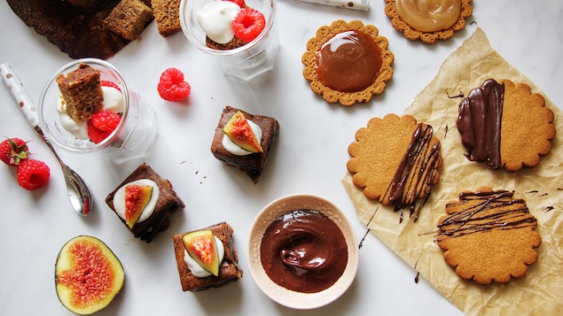 Des verrines avec du pain aux bananes, des brownies au chocolat style petits fours et des biscuits décorés avec du chocolat et du caramel.