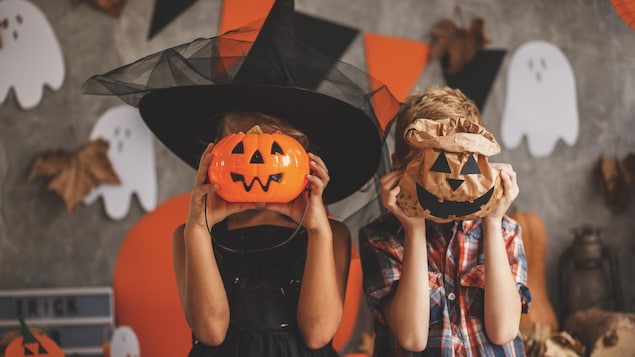 Deux enfants cachent leur visage avec des accessoires d'Halloween.