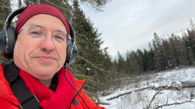 Claude Schryer, dehors en forêt, l'hiver. Il porte des écouteurs.