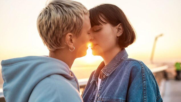 Deux femmes sont sur le point de s'embrasser, devant un coucher de soleil.