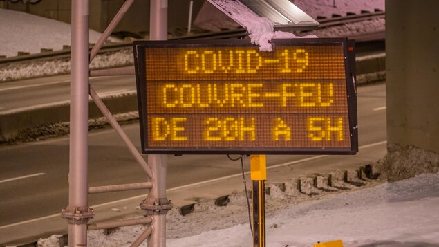 Une affiche électronique au bord de l'autoroute indique les heures du couvre-feu québécois.