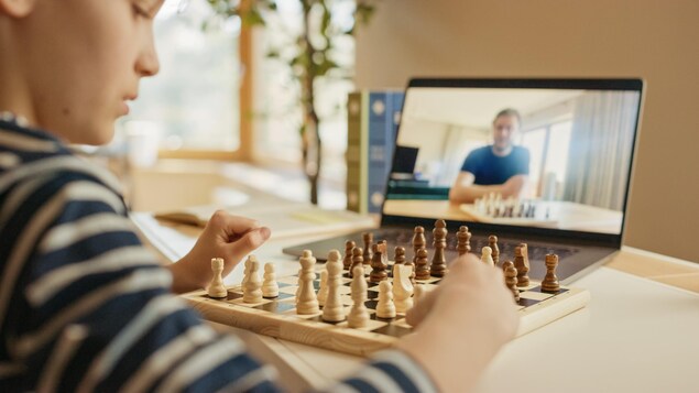 Un garçon joue aux échecs avec une autre personne en ligne.