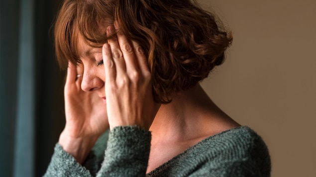 Une femme se tient les tempes en fermant les yeux.