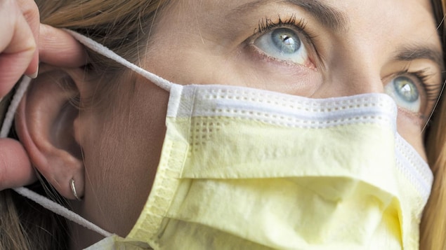 Une femme met son masque pour se protéger de la COVID-19.