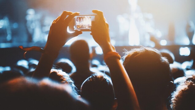 Une personne prend une photo pendant un concert.
