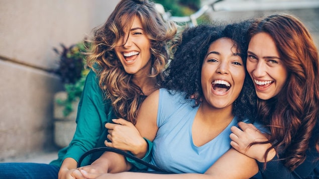 Trois femmes rient ensemble. 