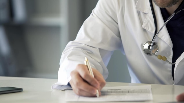 Un médecin écrit sur un papier. 