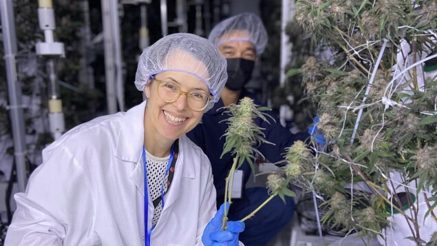 Mireille Roberge, souriante, avec une plante de cannabis à la main.