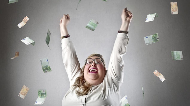 Une femme lève les bras en guise de célébration tandis que des billets de banque lui pleuvent dessus.