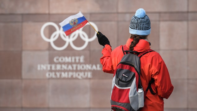Une femme agite un drapeau de la Russie devant le quartier général du Comité international olympique à Pully, en Suisse. Une femme agite un drapeau de la Russie devant le quartier général du Comité international olympique à Pully, en Suisse.
