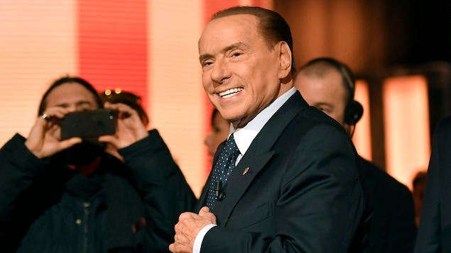Silvio Berlusconi tient son veston en lançant un sourire, sous l'objectif des photographes. Silvio Berlusconi tient son veston en lançant un sourire, sous l'objectif des photographes.