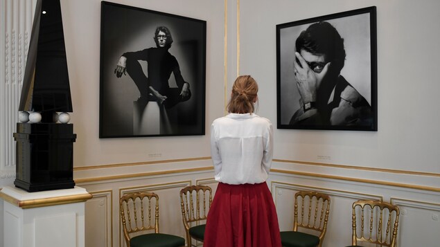 Une femme observe deux portraits d'Yves Saint Laurent au nouveau Musée Yves Saint Laurent, à Paris.