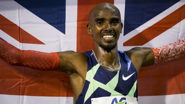 Mo Farah tient un drapeau britannique derrière lui après une course. 