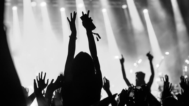 Photo en noir et blanc d'une foule survoltée lors d'un concert de musique.