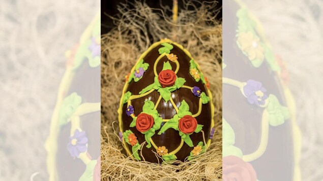 Un œuf en chocolat décoré de fleurs en crémage.