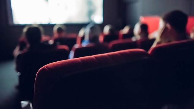 Des gens regardent un film dans une petite salle de cinéma. 