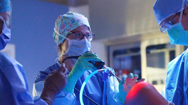 La docteure insère un instrument chirurgical dans le genou d'un patient dans une salle d'opération