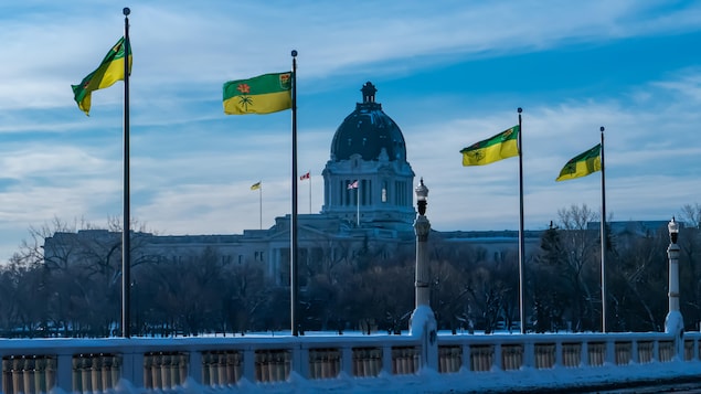 Des drapeaux saskatchewanais devant le Palais législatif de la Saskatchewan en hiver à Regina.