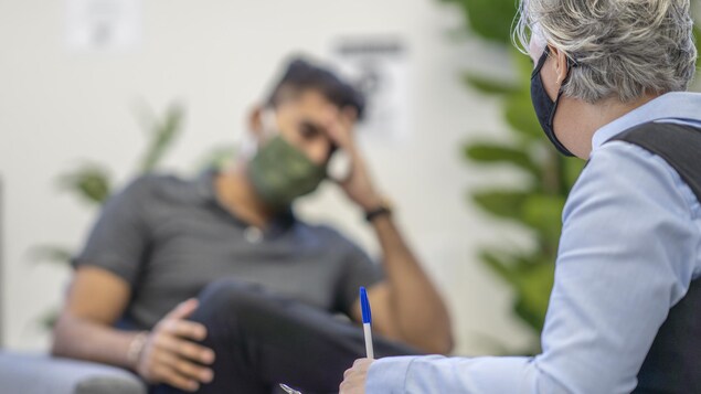 Une thérapeute avec un patient portant un masque de protection.
