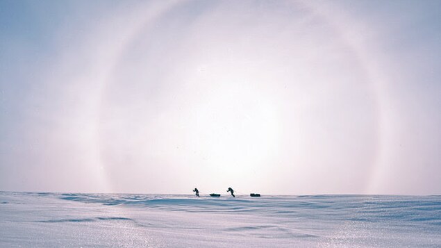 Pascale Marceau et son ami à ski trainant du materiel sur une étendue de neige.
