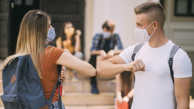 Deux adolescents se saluent avec le coude.