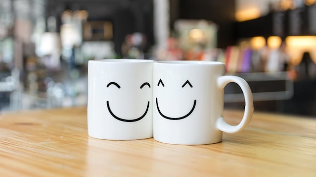 Deux faces de bonhomme souriant imprimées sur des tasses qui se collent l'une contre l'autre.