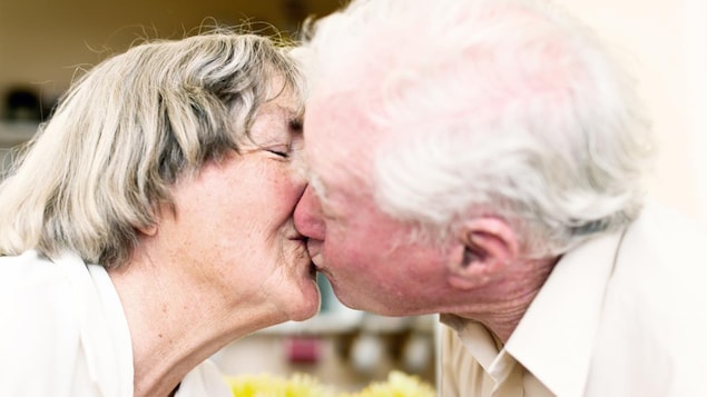 Une femme et un homme âgés se font un baiser sur la bouche.