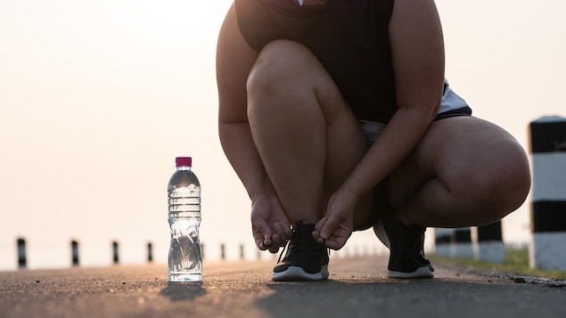 Une femme en train de nouer ses chaussures de course. 