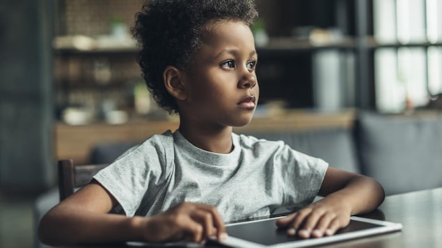 Il regarde au loin les yeux dans le vague, la main posée sur une tablette devant lui.