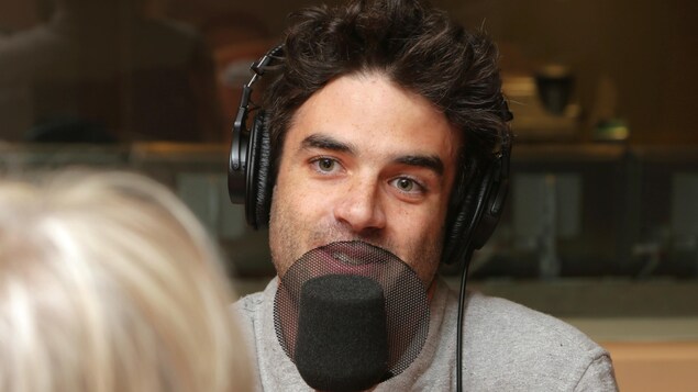 Photo de Geoffroy devant un micro de radio.