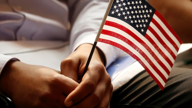 Gros plan sur les mains d'un homme qui tiennent un petit drapeau américain.