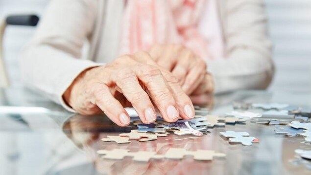 Gros plan sur la main d'une personne agée qui joue à un puzzle.