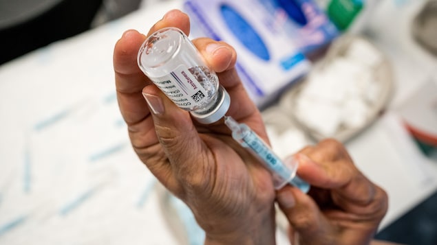Une dame prélève une dose de vaccin AstraZeneca.