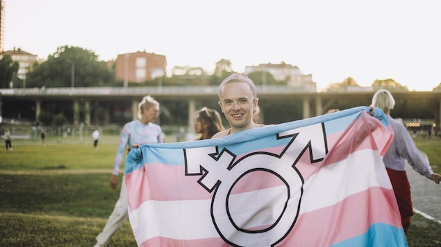 une personne trans avec un drapeau de la fierté transgenre.