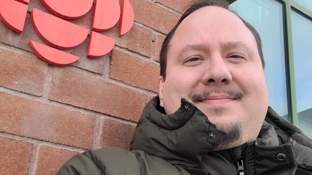 Un ego-portrait de Philippe Paiement avec le logo de Radio-Canada devant la station de la rue Elm à Sudbury.