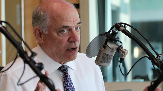 Pierre Fitzgibbon parle en gesticulant devant un micro dans un studio de radio. 