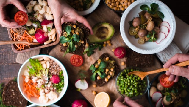 Différents plats végétaliens avec des petits pois, des champignons et différentes salades sont sur une table.