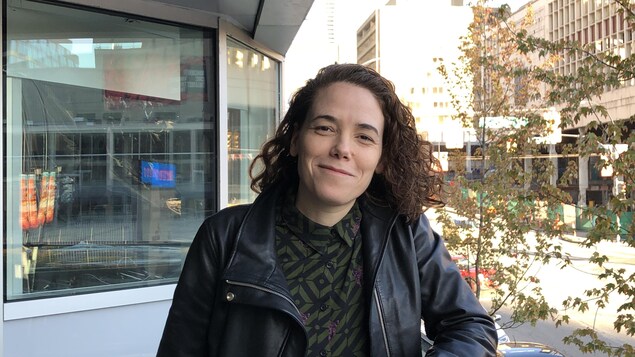 Myriam Verreault porte un manteau en cuir noir et sourit sur un balcon qui montre la rue Georgia à Vancouver.